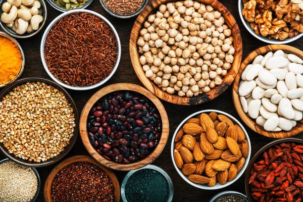 seeds Superfoods, legumes, nuts, seeds and cereals set in bowls on wooden background. Superfood as chia, spirulina, beans, goji berries, quinoa, turmeric, mung bean, buckwheat, lentils, flax seed, wild rice and almond. Copy space, top view